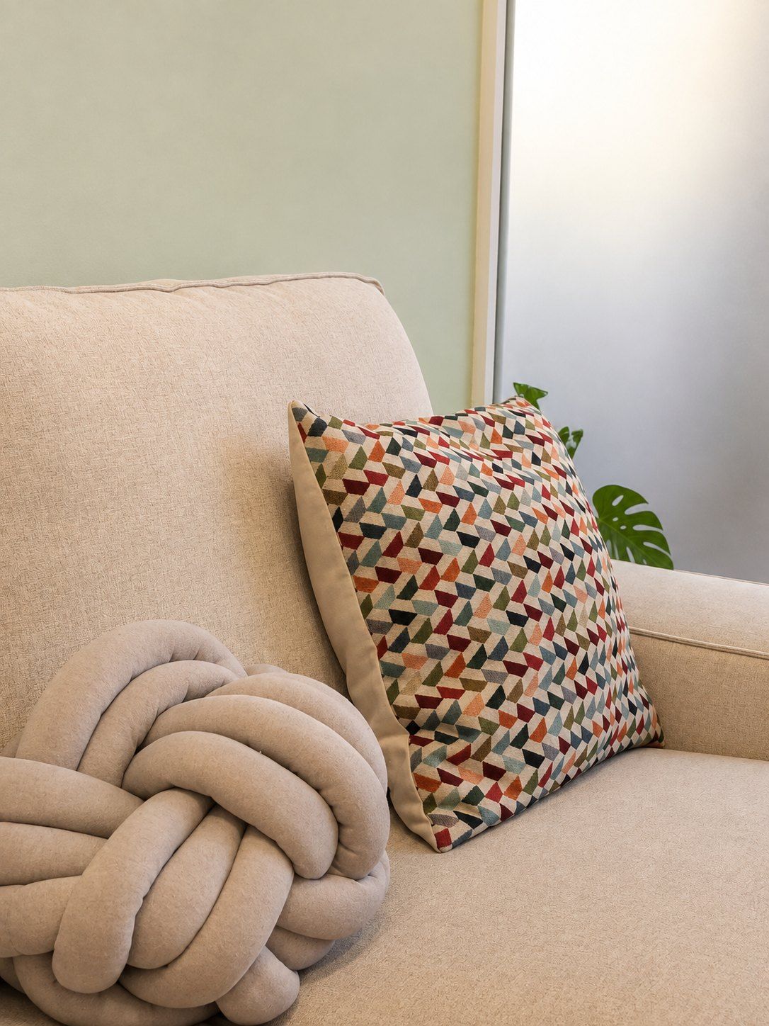 Butaca beige con un cojín de nudo y otro tejido de colores