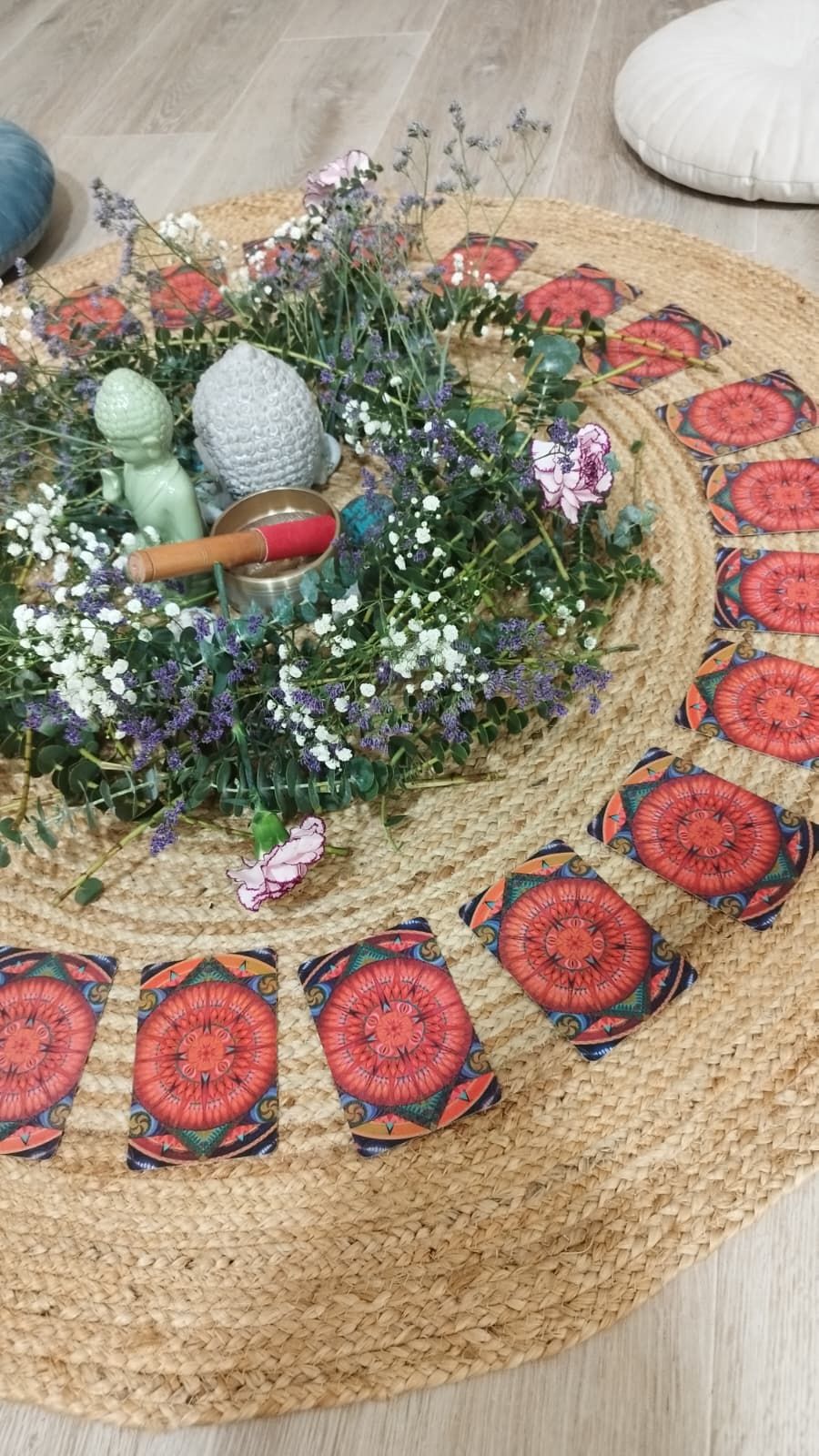 Flores, un cuenco y figuras en el centro de la alfombra, rodeados de cartas ilustradas